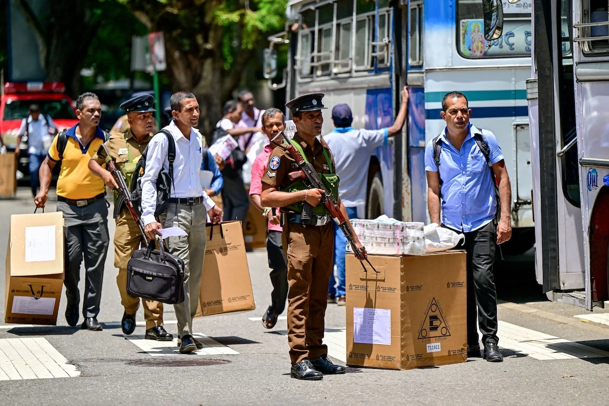 Police assist electoral officials with ballot boxes and other polling materials, as they board a bus on the eve of Sri Lanka's presidential elections in Colombo on Sept. 20, 2024. (AFP)