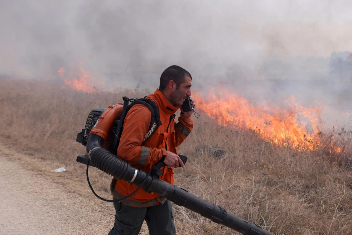 A man attempts to extinguish flames following a rocket attack from Lebanon, amid cross-border hostilities between Hezbollah and Israel, in the Israeli-occupied Golan Heights Sept. 20, 2024. (Reuters)