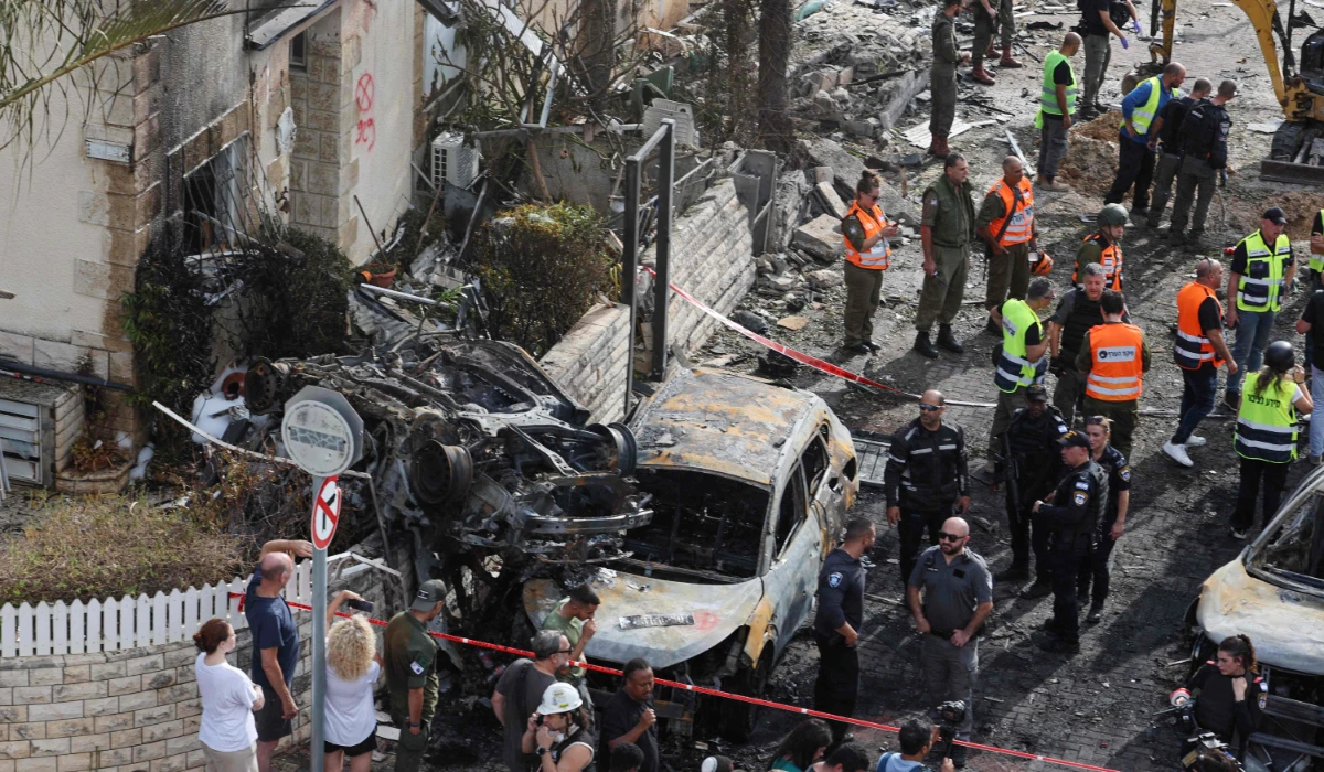 Residents watch as first responders and Israeli security forces gather amid debris and charred vehicles in Kiryat Bialik in the Haifa district of Israel, following a reported strike by Lebanon's Hezbollah on September 22, 2024. (AFP)