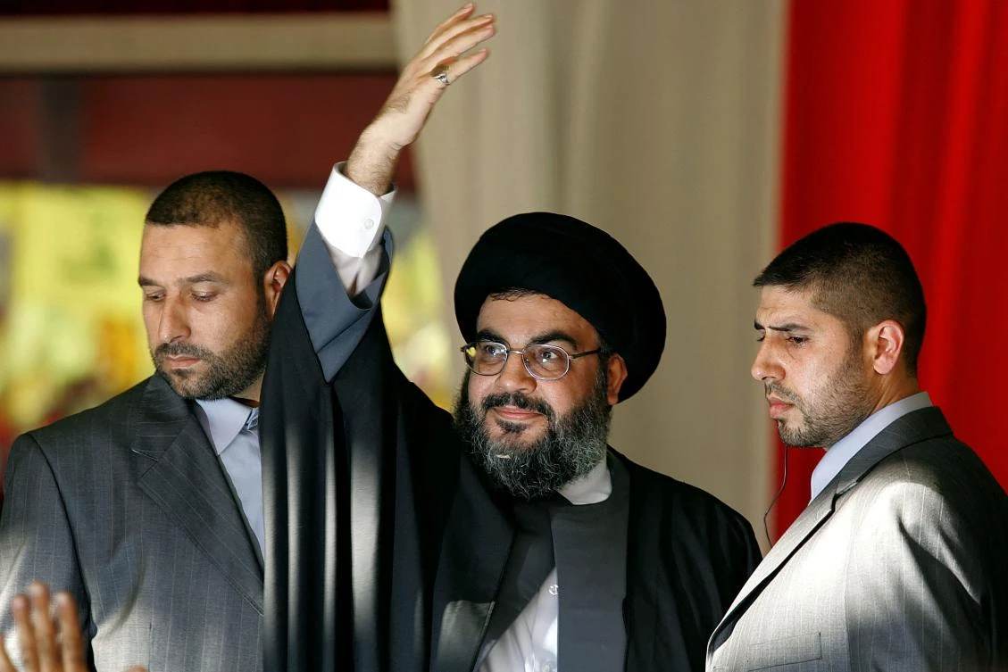 Hezbollah chief Hassan Nasrallah, flanked by two of his bodyguards, waves to the crowds at the massive “divine” rally in the southern suburbs of Beirut, in Sept. 2006. (AFP)