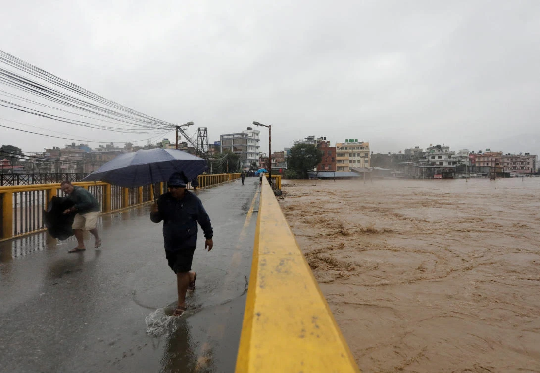People cross the bridge amid the overflowing Bagmati River following heavy rains, in Kathmandu, Nepal September 28, 2024. (REUTERS)
