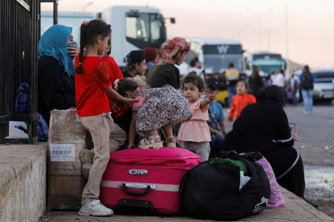 Syrians, who were living in Lebanon and returned to Syria due to ongoing hostilities between Hezbollah and Israeli forces, wait with their belongings at the Syrian-Lebanese border, in Jdaydet Yabous, Syria, September 25, 2024. (Reuters)
