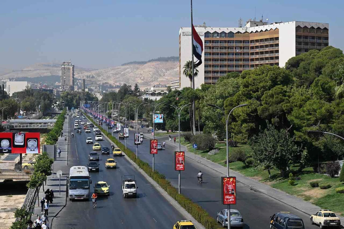 Syrians drive past the Syrian flag at half-mast in the capital Damascus on September 29, 2024, after Syria officially declared a three-day national mourning period following Israel's killing of Lebanon's Hezbollah leader Hassan Nasrallah. (AFP)