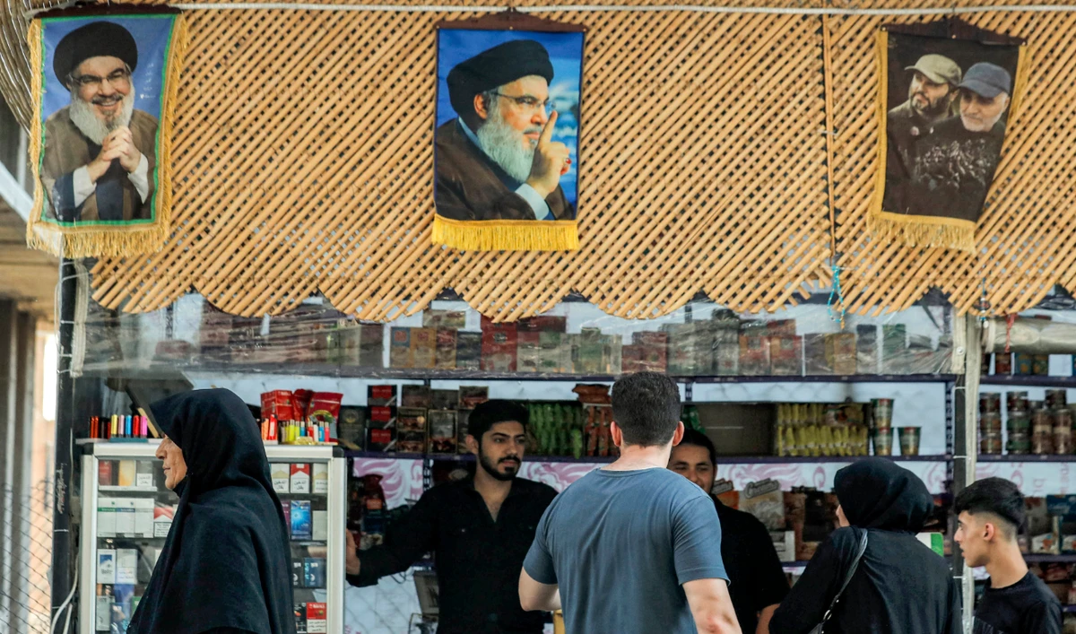 Pictures of Hassan Nasrallah (L and C) hang above a stall as people shop in Damascus' Sayyida Zeinab district on September 29, 2024. (AFP/File)