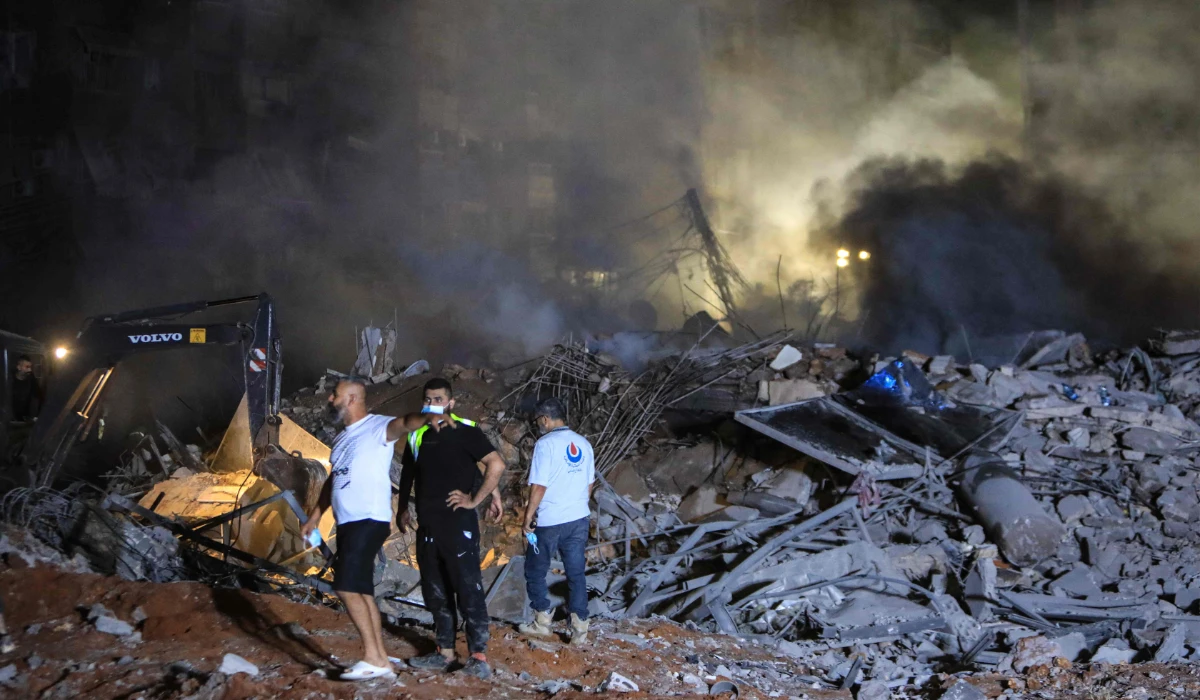 Rescuers stand on the rubble of a builiding destroyed in an Israeli air strike in Beirut on September 27, 2024. (AFP)