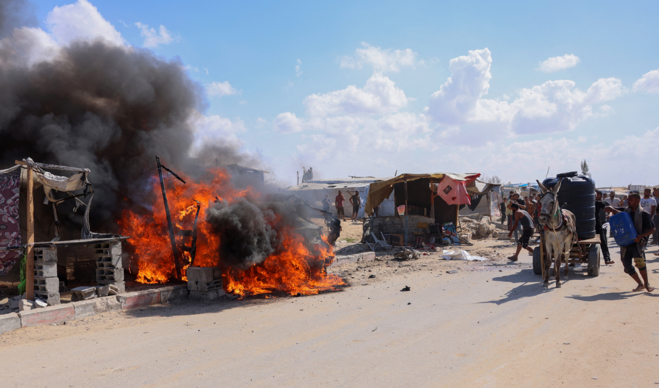 Displaced Palestinians douse a burning car with water after it was hit in an Israeli strike in Khan Yunis in the southern Gaza Strip city on October 1, 2024. (AFP)