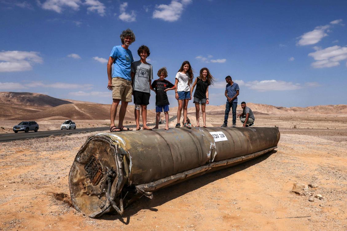 People stand on top of the remains of an Iranian missile in the Negev desert near Arad, on Oct. 2, 2024, in the aftermath of an Iranian missile attack on Israel. (AFP)