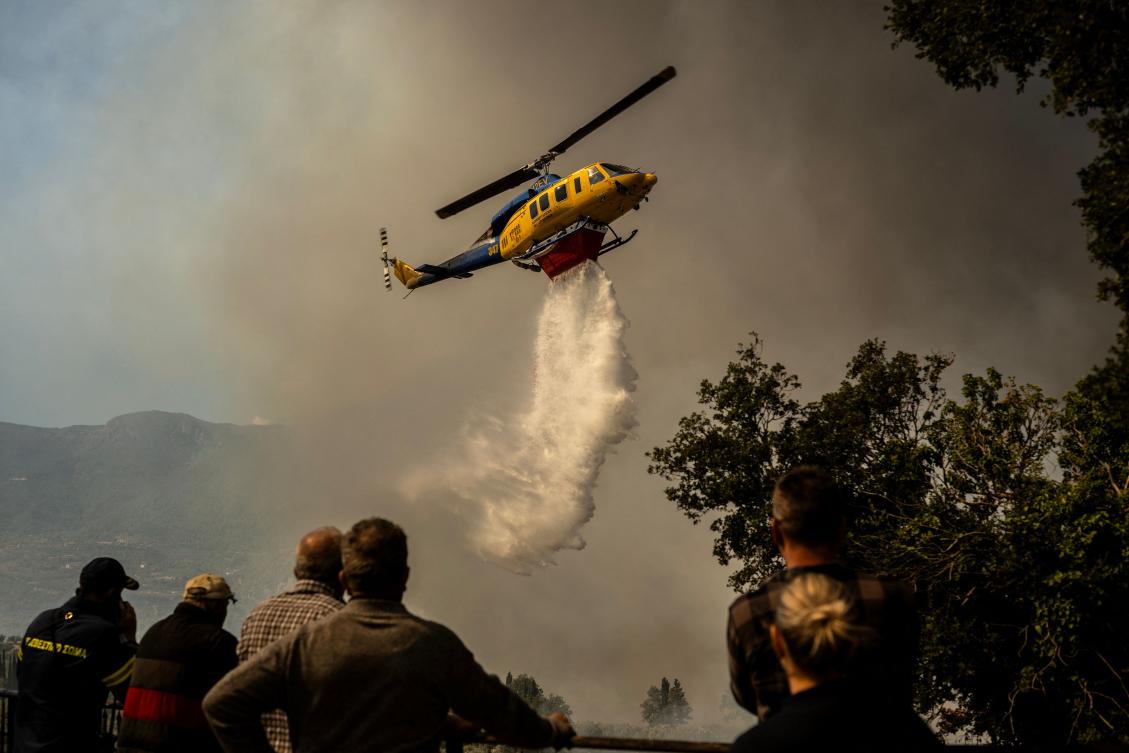 A firefighting helicopter drops water drop as a wildfire burns in the village of Pyrgos, near Corinth, on Sept. 30, 2024. (AFP)