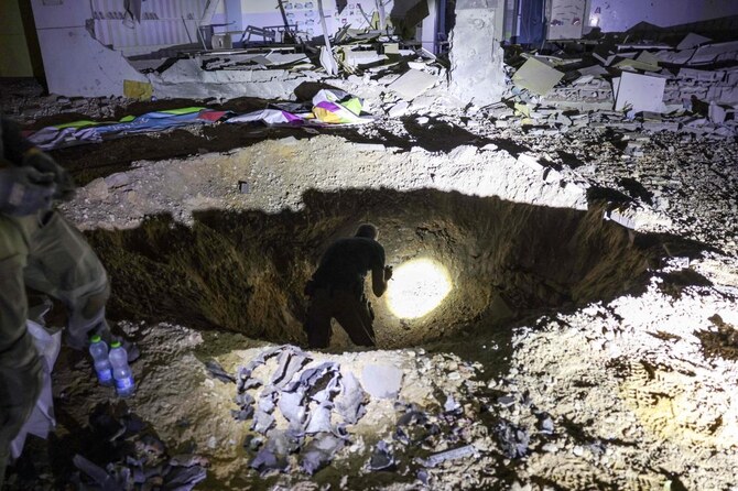 Members of Israel’s Home Front Command and police forces inspect a crater left by an exploded projectile at a heavily-damaged school building in Israel’s southern city of Gedera on Oct. 1, 2024, after Iran launched a barrage of missiles at Israel. (AFP)