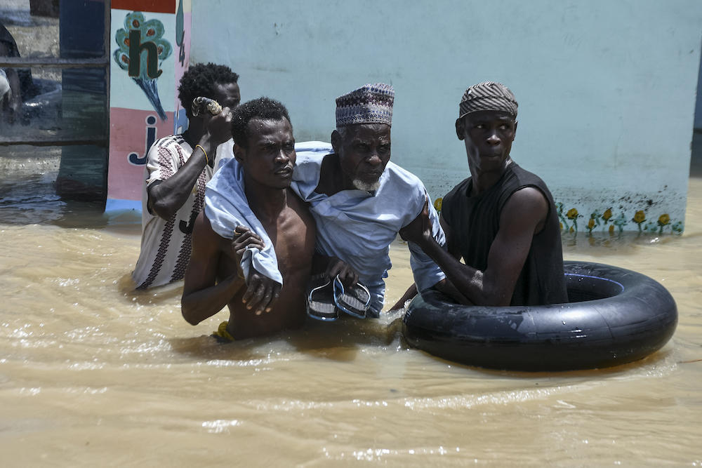 Above, rescuers help an elderly man wade through flood water in Maiduguri on Sept. 12, 2024. (AFP)