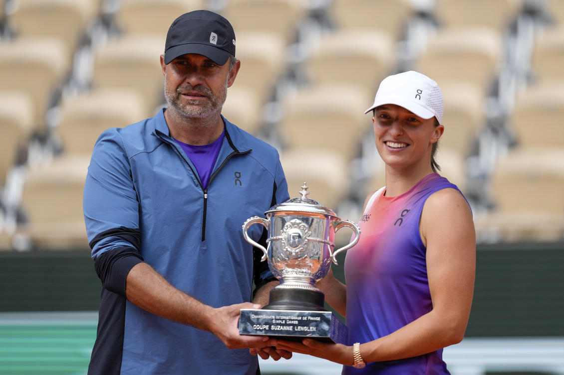 World number one Iga Swiatek and her coach Tomasz Wiktorowski hold the trophy after she won the women’s final of the French Open tennis tournament on June 8, 2024. (AP)