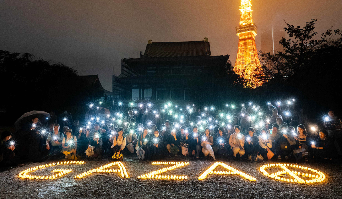 People hold up their lit mobile phones next to a LED candle sign on the ground reading "Gaza" during a candlelight vigil in front of Zojoji temple in Tokyo on October 5, 2024, to call for a ceasefire in Gaza. (AFP)