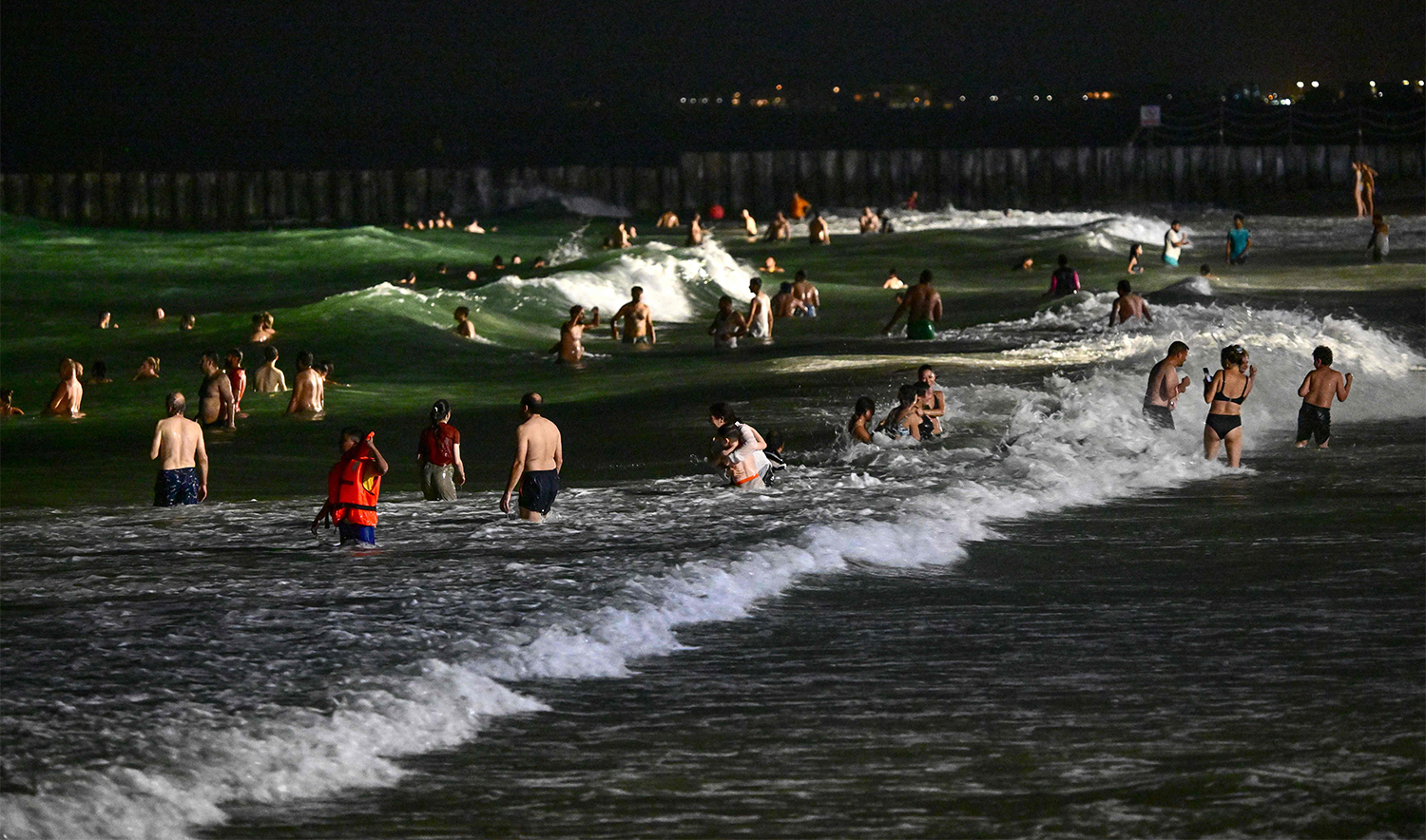 People swim at the Umm Suqeim beach in Dubai during the night of October 5, 2024. (AFP)