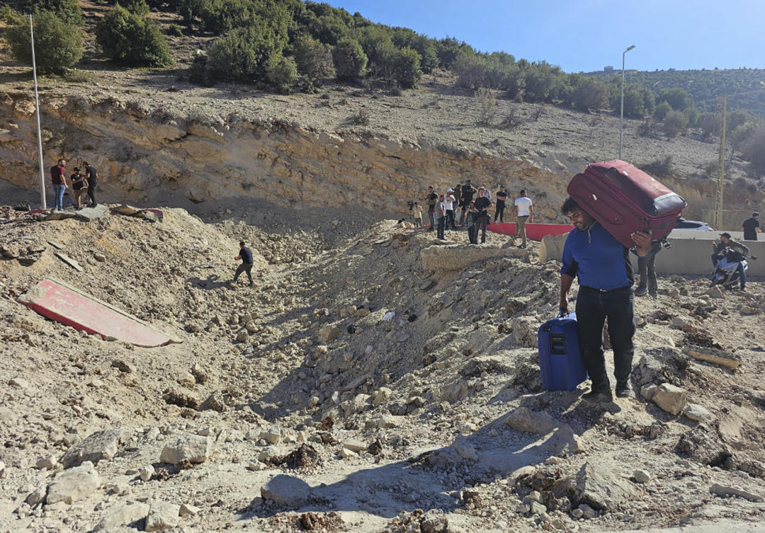 A Syrian man crosses on foot into Syria through a crater caused by an Israeli airstrike to cut the road between the Lebanese and Syrian checkpoints, at the Masnaa crossing in Lebanon, Friday, Oct. 4, 2024. (AP)