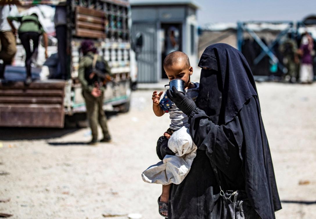 A Syrian woman helps a child to drink as she waits with family members inside the Kurdish-run al-Hol camp, which holds relatives of suspected Islamic State (IS) group fighters in the northeastern Hasakeh governorate, before being released from the camp to return home in the northern Raqqa region, on July 15, 2021. (File/AFP)