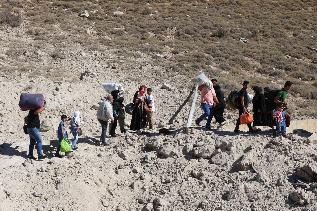 On Friday, an AFP photographer saw people carrying bags and children as they walked around a crater where a strike had hit. (AFP)