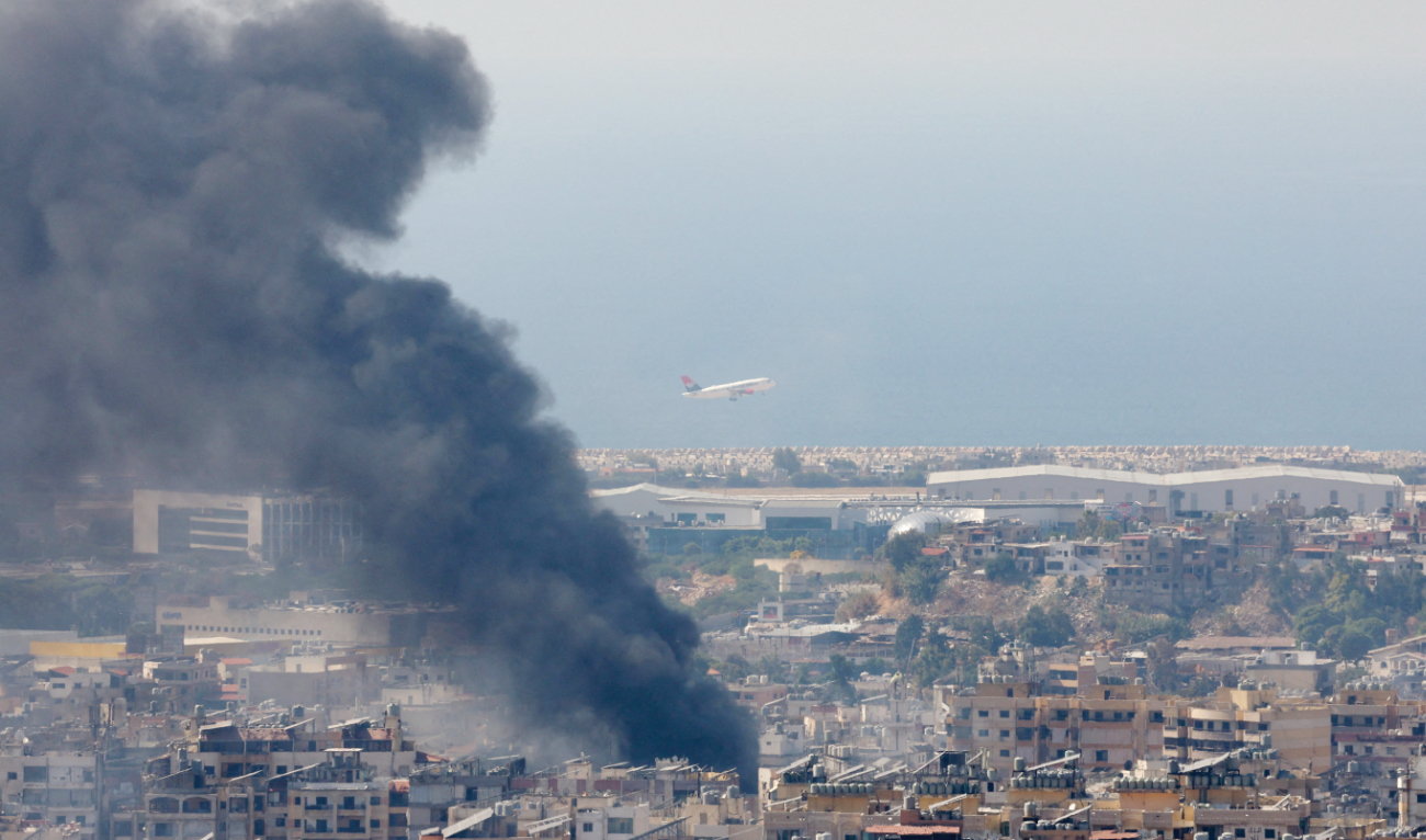 Smoke rises in Beirut’s southern suburbs following a strike amid the ongoing hostilities between Hezbollah and Israel. In the background, a plane takes off from the city’s airport. (Reuters)