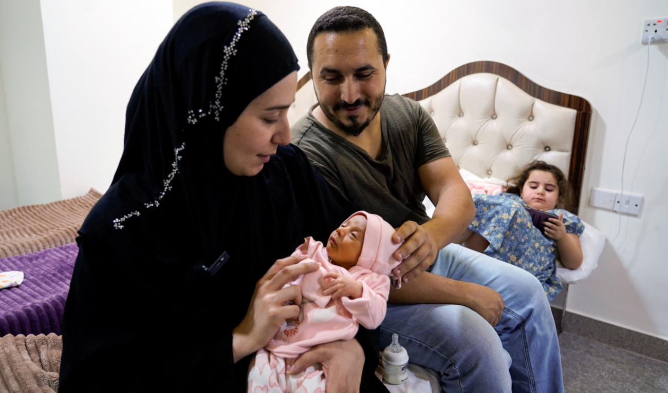 Lubana Ismail, a displaced Lebanese woman who fled from her home in Tyre due to Israeli bombardments in Southern Lebanon, holds her newborn baby girl, Zahraa, to whom she gave birth in Iraq, as she sits with her family at a hotel in Najaf, Iraq, October 7, 2024. (Reuters)