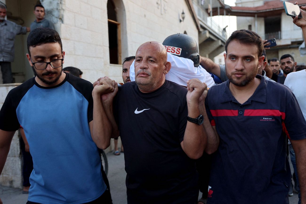 People carry the body of Al-Aqsa TV journalist Muhammad Al-Tanani, who was killed during Israeli bombardment in the northern Gaza Strip, as he is prepared for burial at Al-Ahli Arab hospital. (AFP)