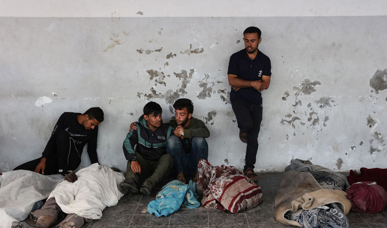 Ali Assaf (C), 20, reportedly the only survivor from his family killed in an overnight Israeli airstrike in the Jabalia refugee camp in the northern Gaza Strip, is comforted by two young men as mourns near the bodies of his relatives in front of the Al-Maamadani on October 12, 2024. (AFP)