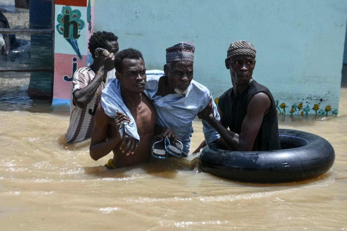 People help an elderly man wade through flood water in Maiduguri on September 12, 2024. (File/AFP)