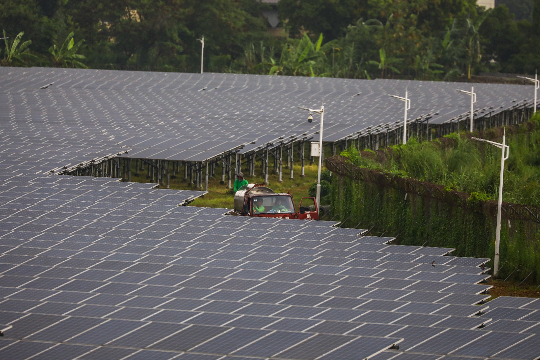 Workers in a utility truck ride past solar panels at a solar energy farm in Valenzuela, suburban Manila. (AFP/File)