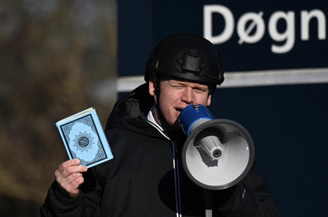 Far-right politician Rasmus Paludan holds up a copy of the Qur’an as he speaks in front of a mosque in Copenhagen. (AFP/File Photo)