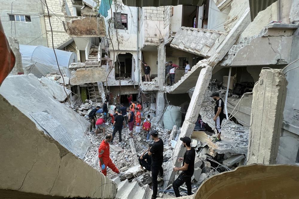 Residents and rescue teams inspect the damage following an overnight Israeli airstrike on the Ain al-Helweh camp. (AFP)