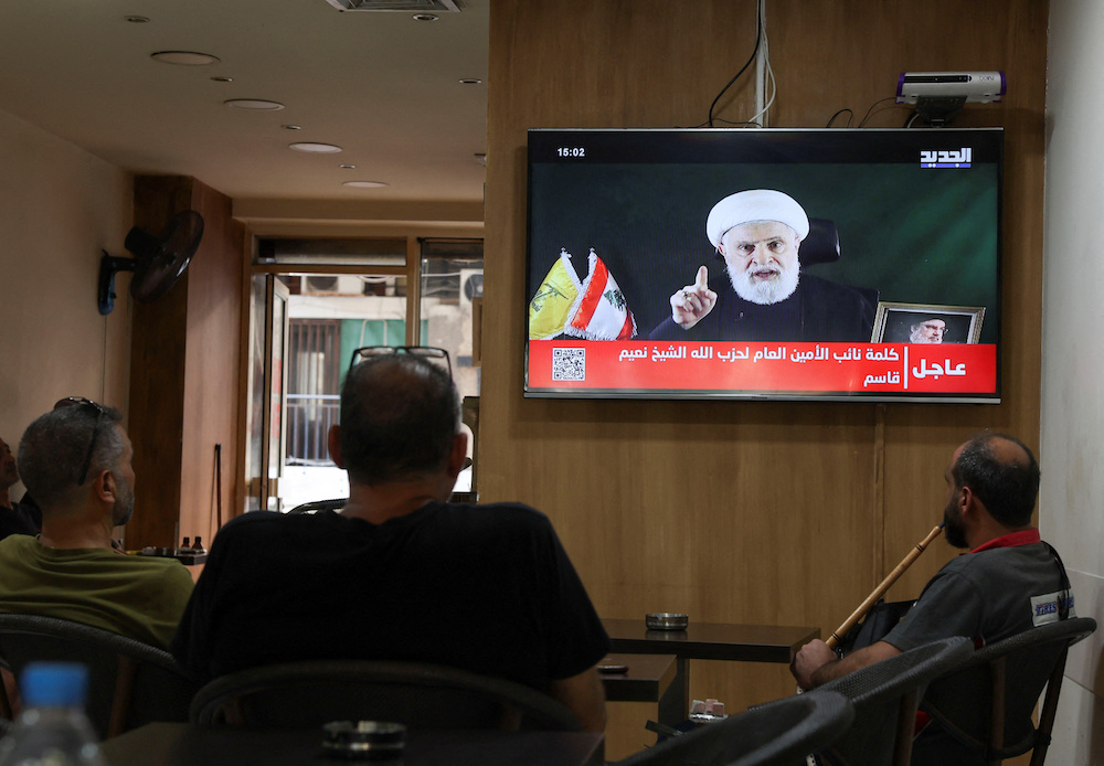 Above, people watch Hezbollah deputy leader Sheikh Naim Qassem delivering a televised address as they sit in a cafe in Beirut on Oct. 15, 2024. (Reuters)