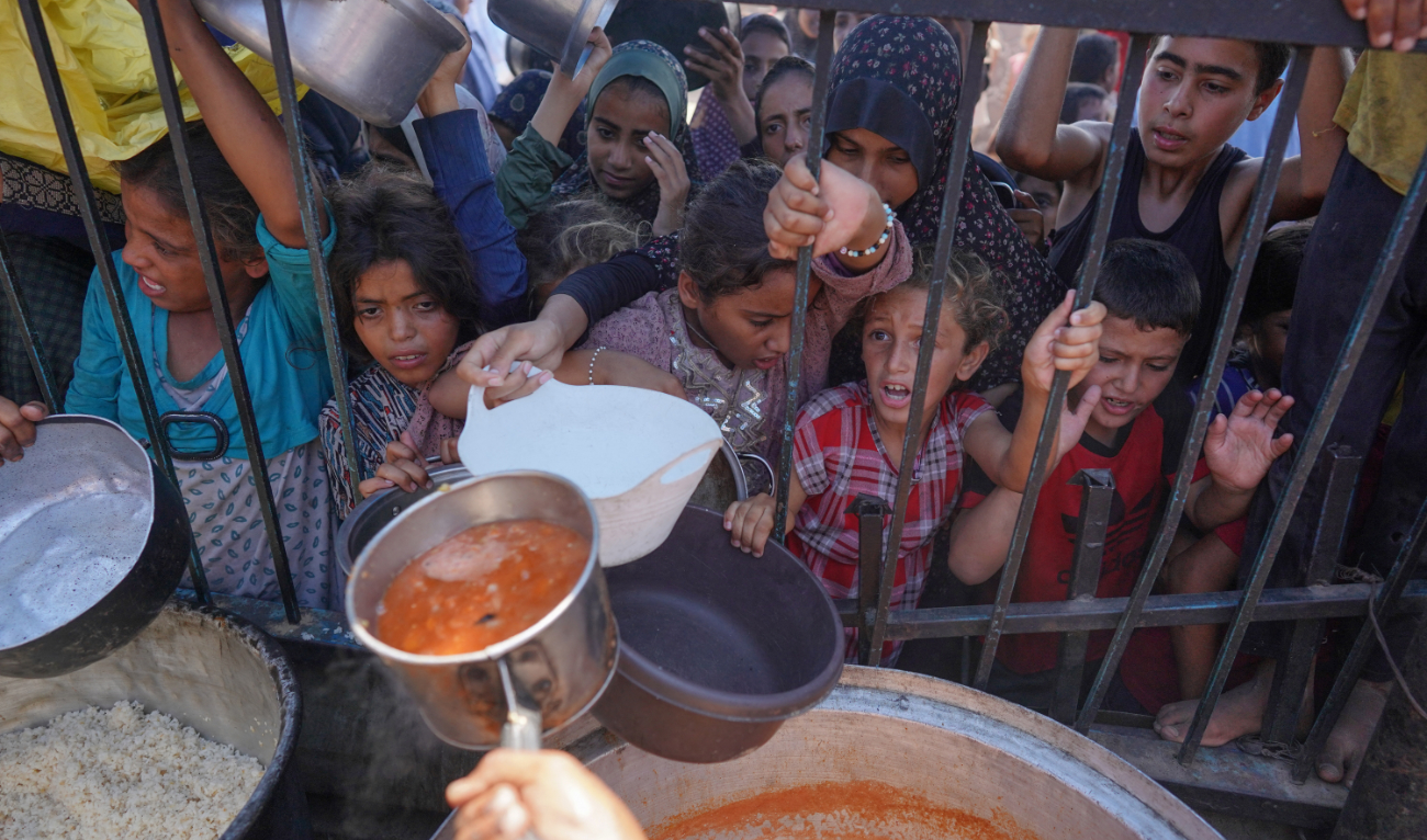 Palestinians receive cooked food rations as part of a volunteer initiative in a makeshift displacement camp in Mawasi Khan Yunis in the besieged Gaza Strip on September 3, 2024. (AFP)