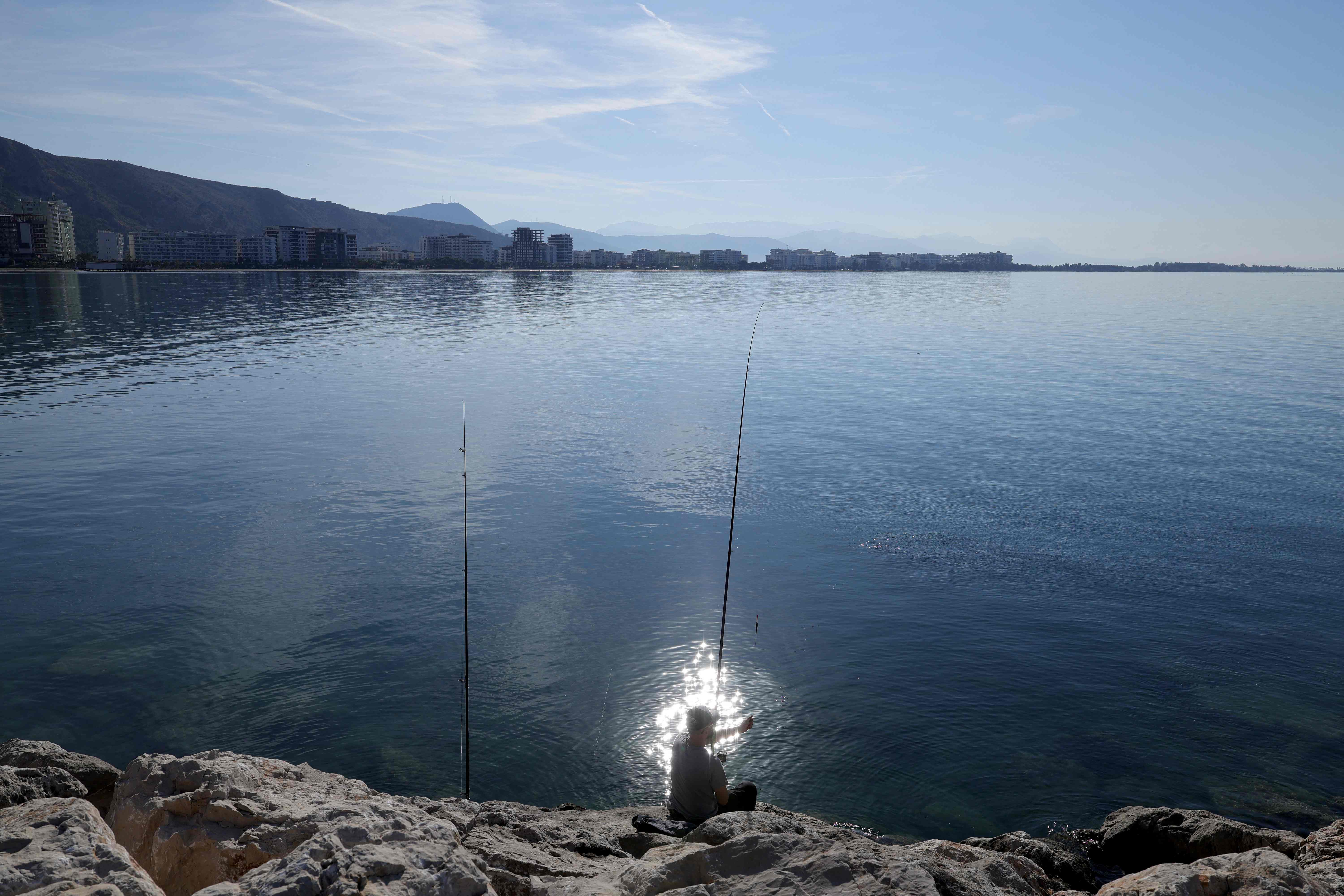 A local resident fishes near the port in Shengjin, on October 15, 2024. (AFP)