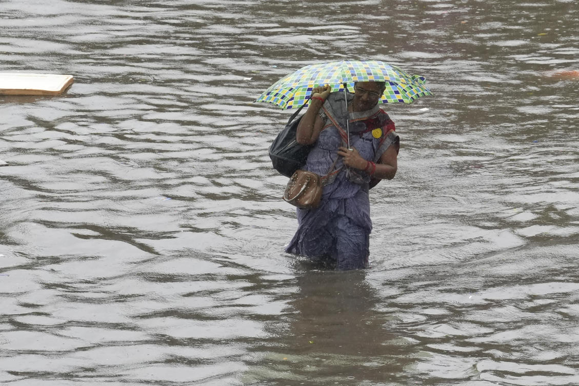 Above, a woman wades through a flooded street during heavy rain in Chennai on Oct. 15, 2024. (AP)