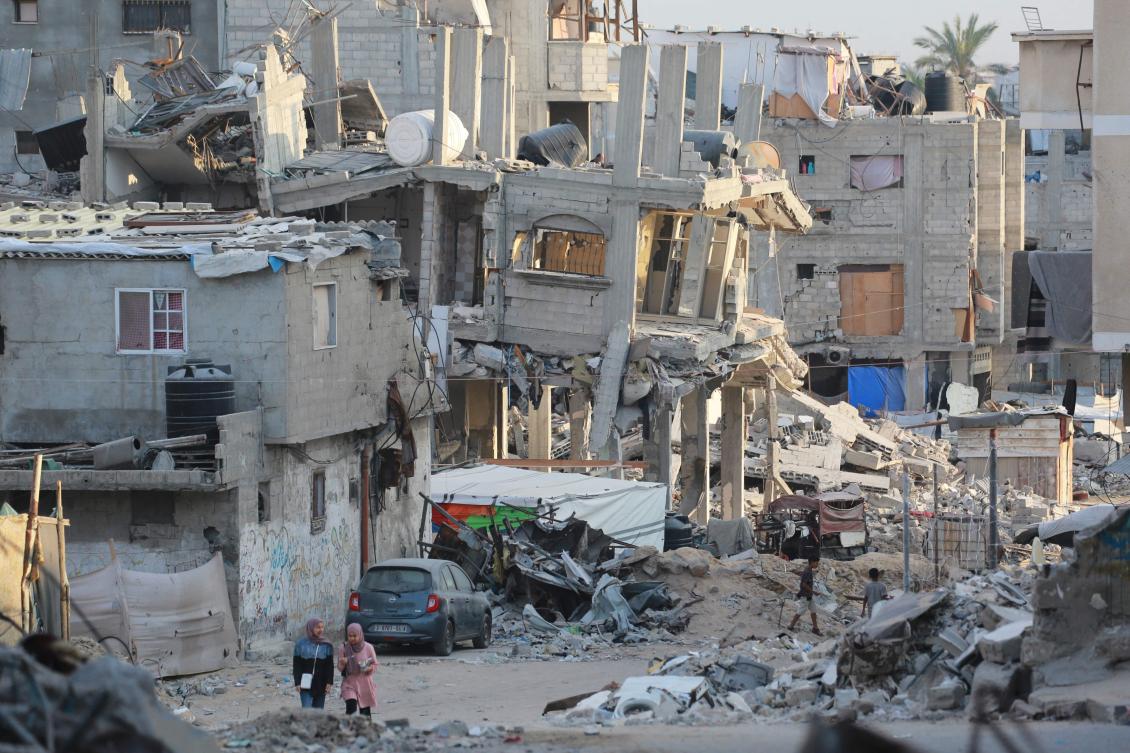 People walk past destroyed buildings in Khan Yunis in the southern Gaza Strip on October 17, 2024, amid the ongoing war between Israel and the Palestinian militant group Hamas in the besieged Palestinian territory. (AFP)