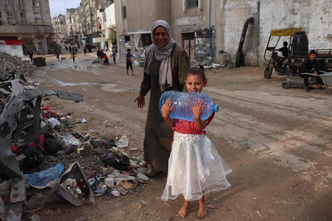 TOPSHOT — A Palestinian girl helps her mother carry a jerrican of water back from a water distribution point in Khan Yunis in the southern Gaza Strip on October 17, 2024, amid the ongoing war between Israel and the Palestinian militant group Hamas in the besieged Palestinian territory. (AFP)