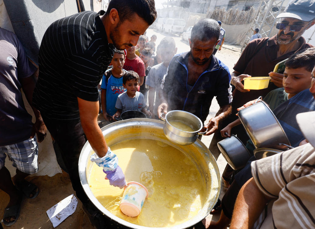 Palestinians gather to receive food cooked by a charity kitchen in Khan Younis in the southern Gaza Strip, October 16, 2024. (Reuters)
