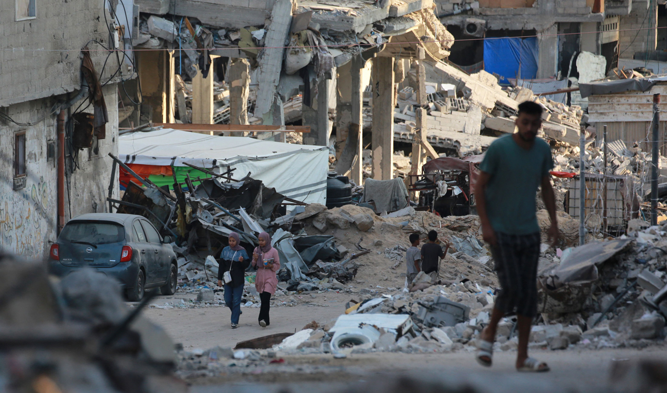 People walk past destroyed buildings in Khan Yunis in the southern Gaza Strip on October 17, 2024, amid the ongoing war between Israel and Hamas in the besieged Palestinian territory. (AFP)