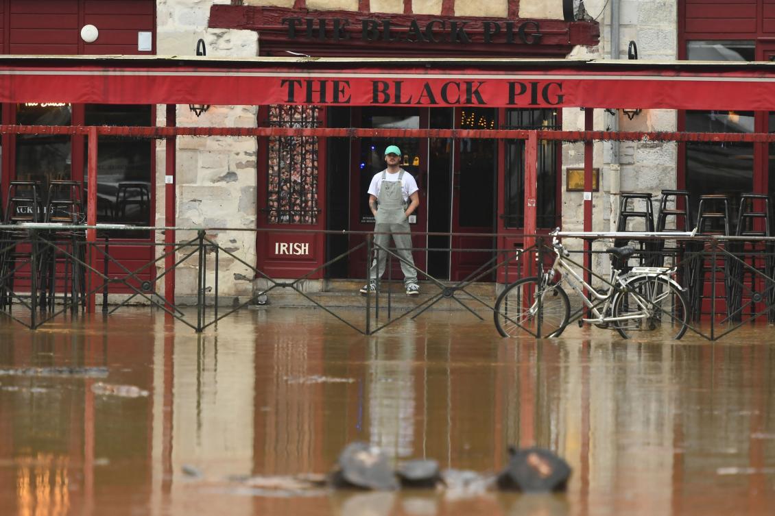A man looks on to a flooded street by the overflowing of the river La Nive, in front of a pub in Bayonne, south-western France on October 17, 2024. (AFP)