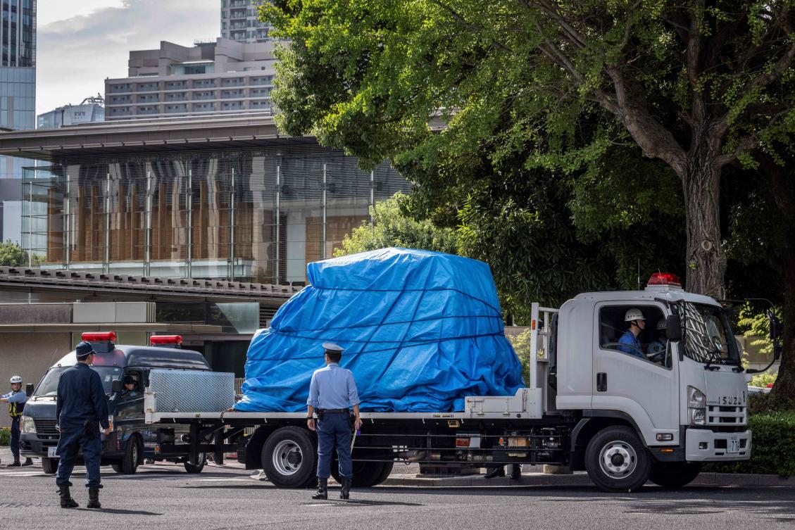 Police officers remove a vehicle which crashed into a barricade outside the prime minister's official residence in central Tokyo on October 19, 2024, after a man threw Molotov cocktail-like objects outside the ruling party's headquarters building, hit a riot police vehicle, and then later drove into the barricade. (AFP)