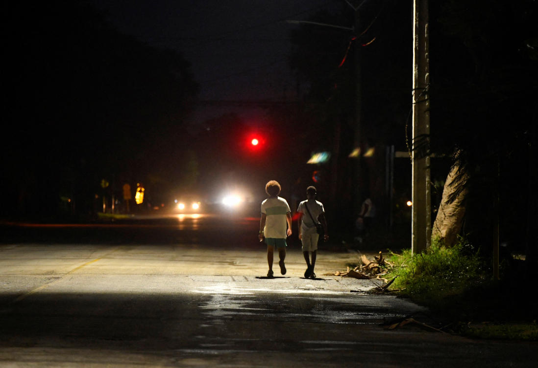 People walk along a street near a street lamp as Cuba's government said on Saturday it had made some progress in gradually re-establishing electrical service across the island, in Havana, Cuba October 19, 2024. (Reuters)