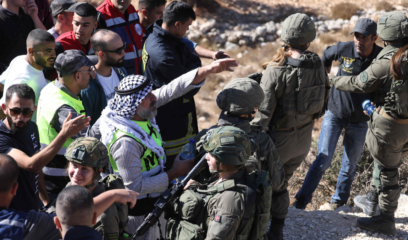 Israeli soldiers block a road preventing Palestinian farmers from picking olives in their fields. (AFP)