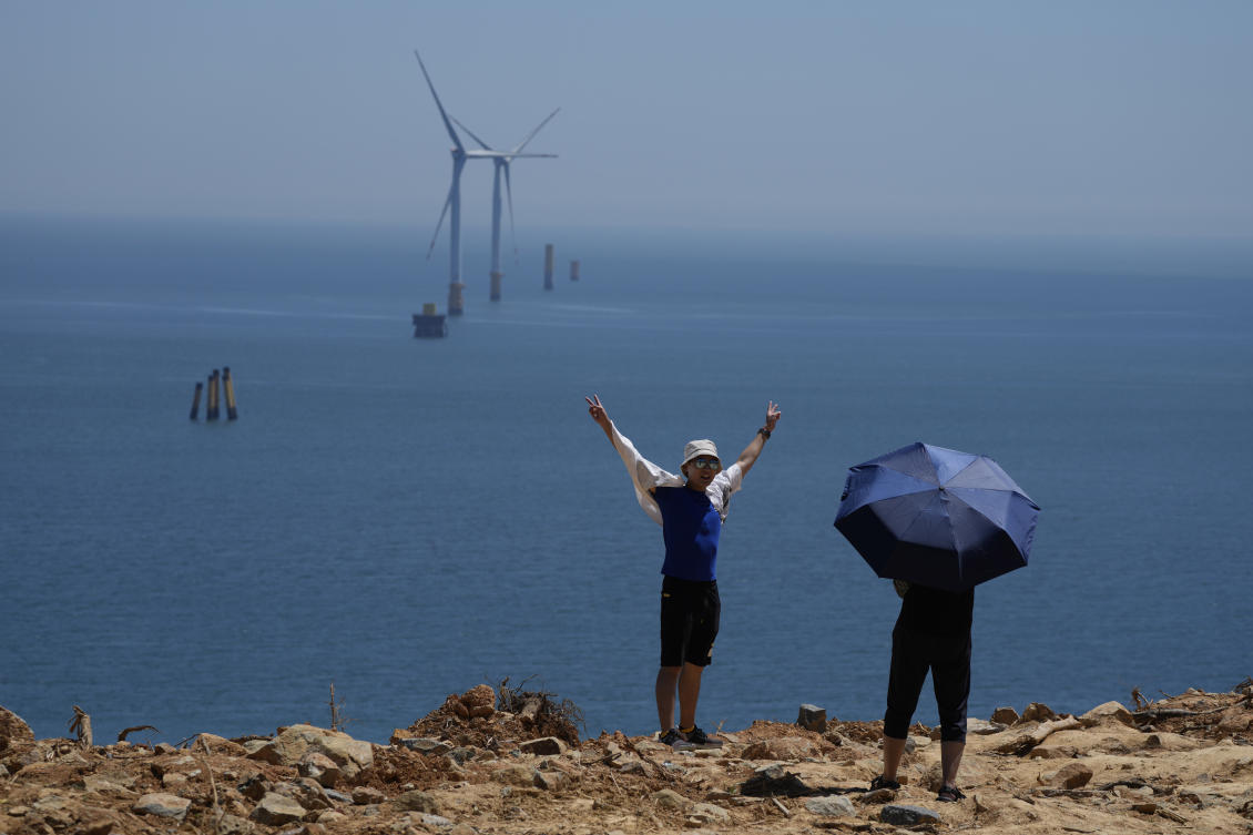 China is holding live-fire drills were being held near the Pingtan islands off Fujian province. Above, a tourist poses for photos near turbines along the Taiwan Straits in Pingtan on Aug. 6, 2022. (AP)