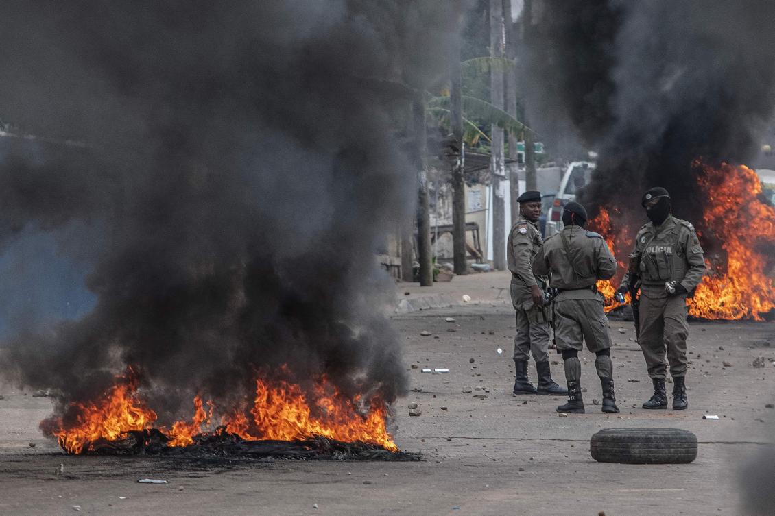 Mozambican anti-riot police stand among burning barricades during the aftermath of a march in Maputo on Oct. 21, 2024 to denounce fraud during the presidential election. (AFP)