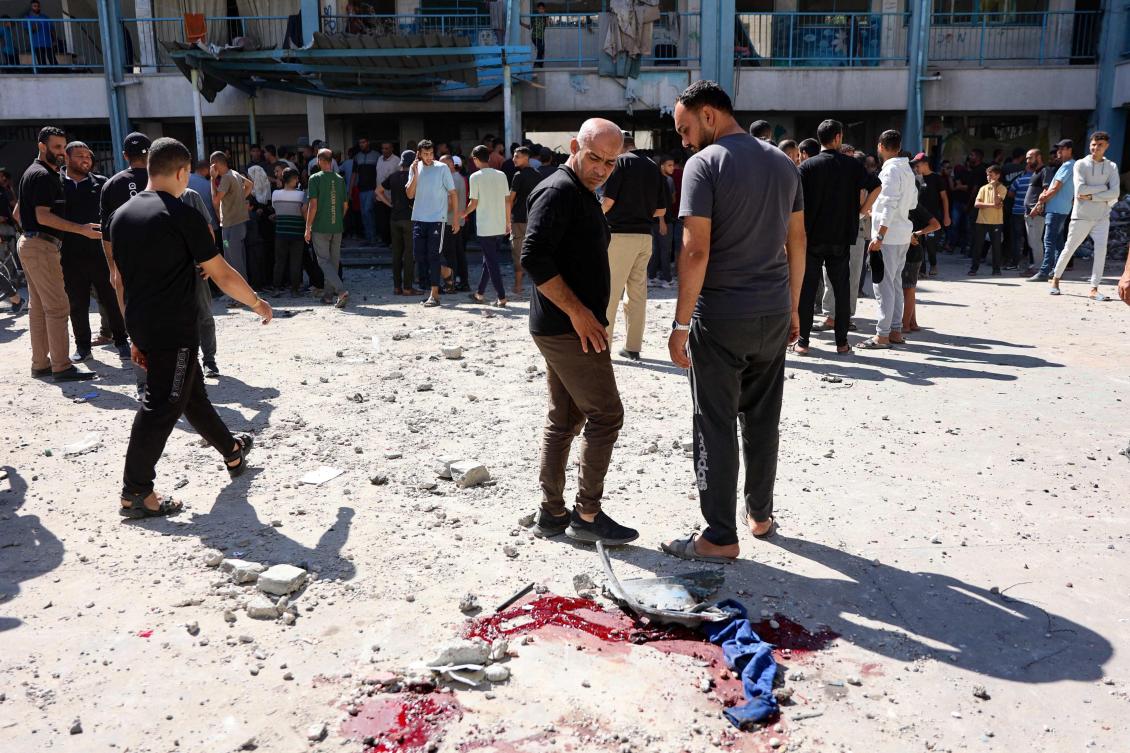 Displaced Palestinians stare at blood stains in the courtyard of UN school-turned-refuge in the Al-Shati refugee camp near Gaza City in the northern Gaza Strip, following a reported Israeli strike. (File/AFP)