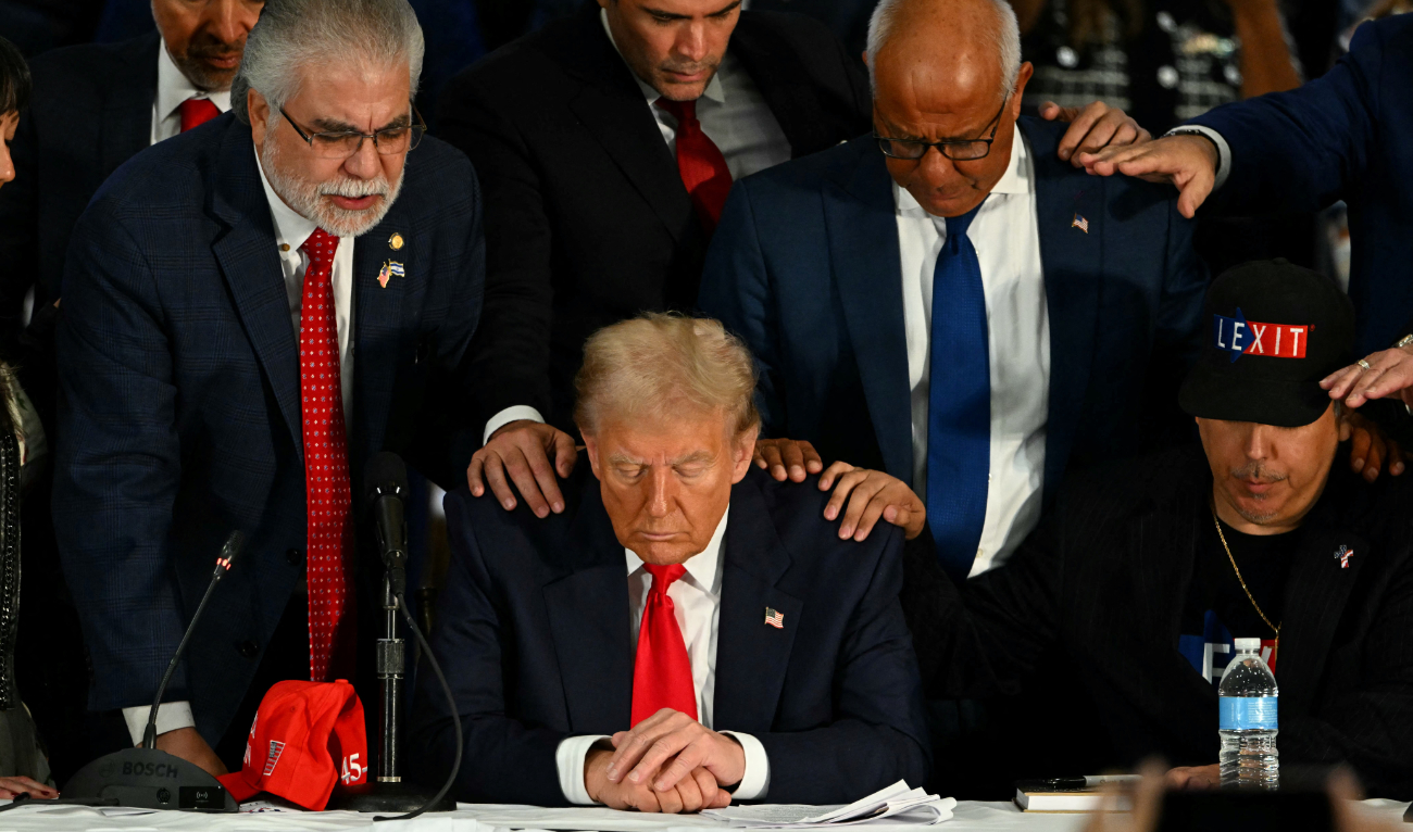 Former US President and Republican presidential candidate Donald Trump prays during a roundtable discussion with Latino community leaders at Trump National Doral Miami resort in Miami, Florida, on October 22, 2024. (AFP)