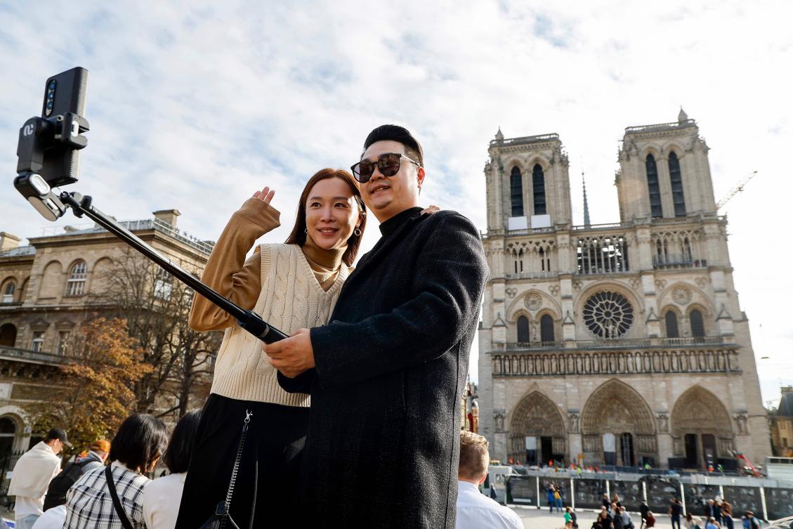 US tourists pose for a selfie photograph in front of the Notre-Dame de Paris Cathedral during the renovation of various parts of the Notre-Dame de Paris Cathedral in Paris, on Oct. 21, 2024. (AFP)