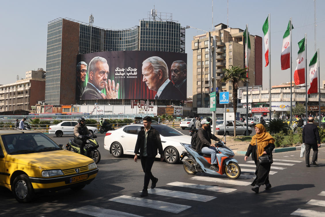 Iranians walk next to an anti-US and Israeli billboard with pictures of Iranian President Masoud Pezeshkian and Iranian Armed Forces Chief of Staff, Major General Mohammad Bagheri and US President Joe Biden and Israel's Prime Minister Benjamin Netanyahu, on a street in Tehran. (File/Reuters)
