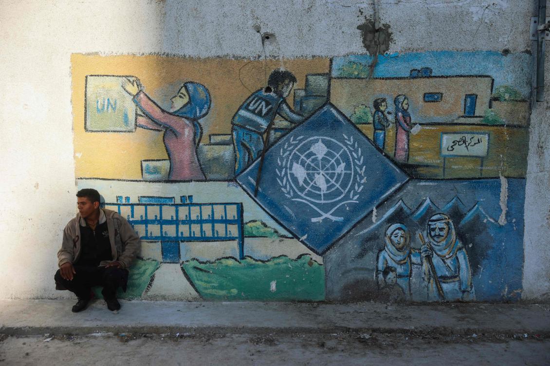 A man squats by a wall bearing a mural representing the UNRWA (United Nations Relief and Works Agency) at the aid agency's center at the Nuseirat camp for Palestinian refugees in the central Gaza Strip on October 29, 2024. (File/AFP)