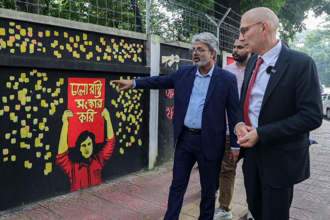 United Nations High Commissioner for Human Rights Volker Turk, right, looks at graffiti on the walls of Dhaka university campus in Dhaka on Oct. 29, 2024. (AFP)