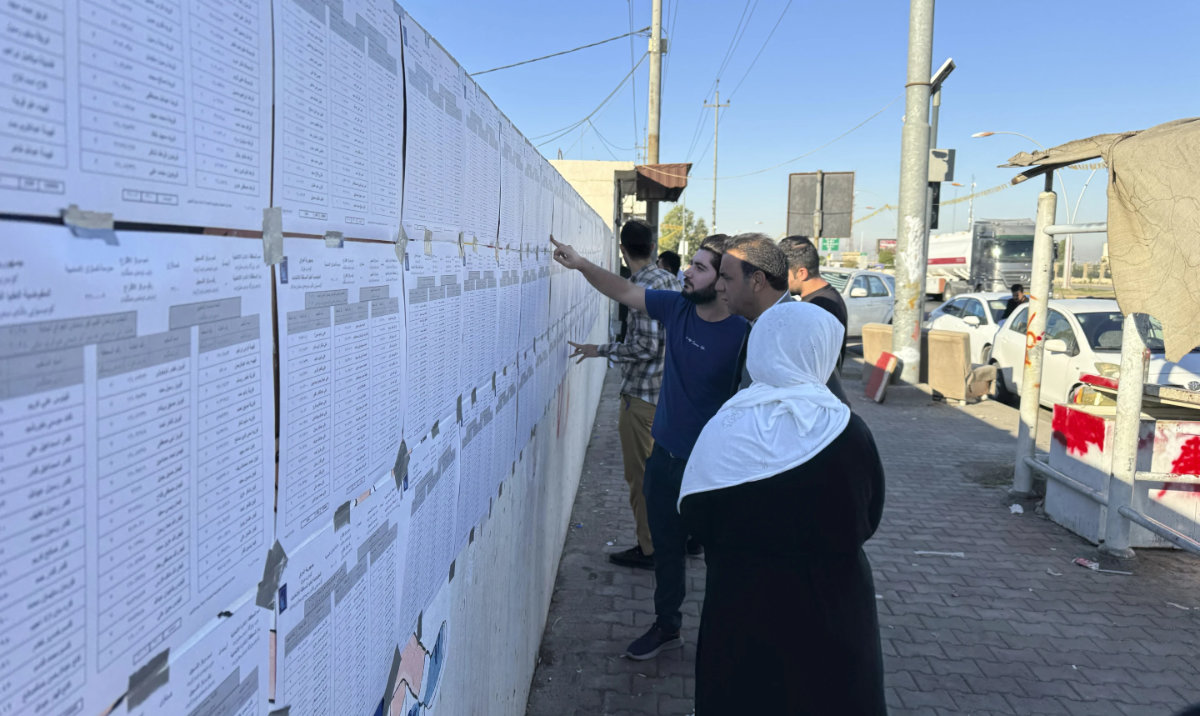 People checks candidates lists during parliamentary elections of Iraq's semi-autonomous northern Kurdish region, in Irbil, Sunday, Oct. 20, 2024. (AP)