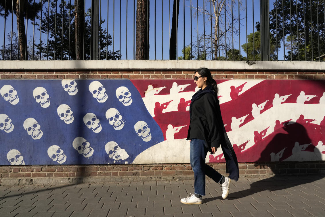 Above, an Iranian woman walks past a satirized image of the US flag on the wall of former US embassy in Tehran on Oct. 22, 2024. Many Iranians are split on which US candidate would be better for their country – if at all.(AP)